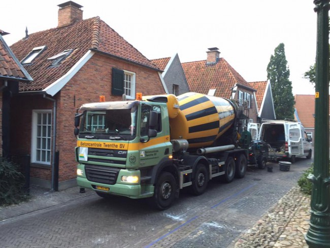 De betonwagen staat voor het huis geparkeerd en laat de beton in de pomp lopen